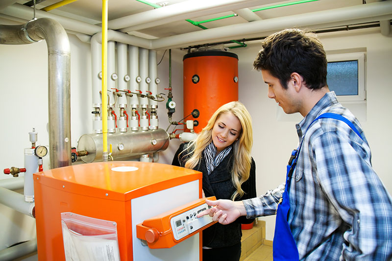 Kundendienst Monteur wartet die Heizung einer Kundin